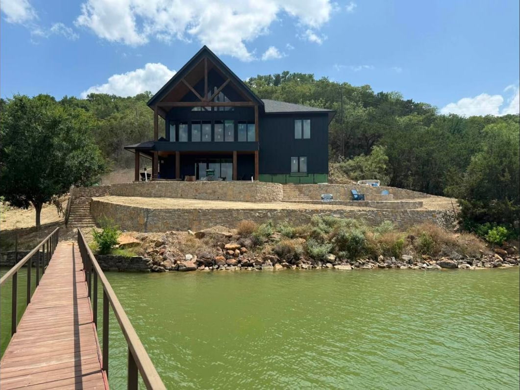 Tiered stone retaining walls holding the building pad above the lake, seen from the dock