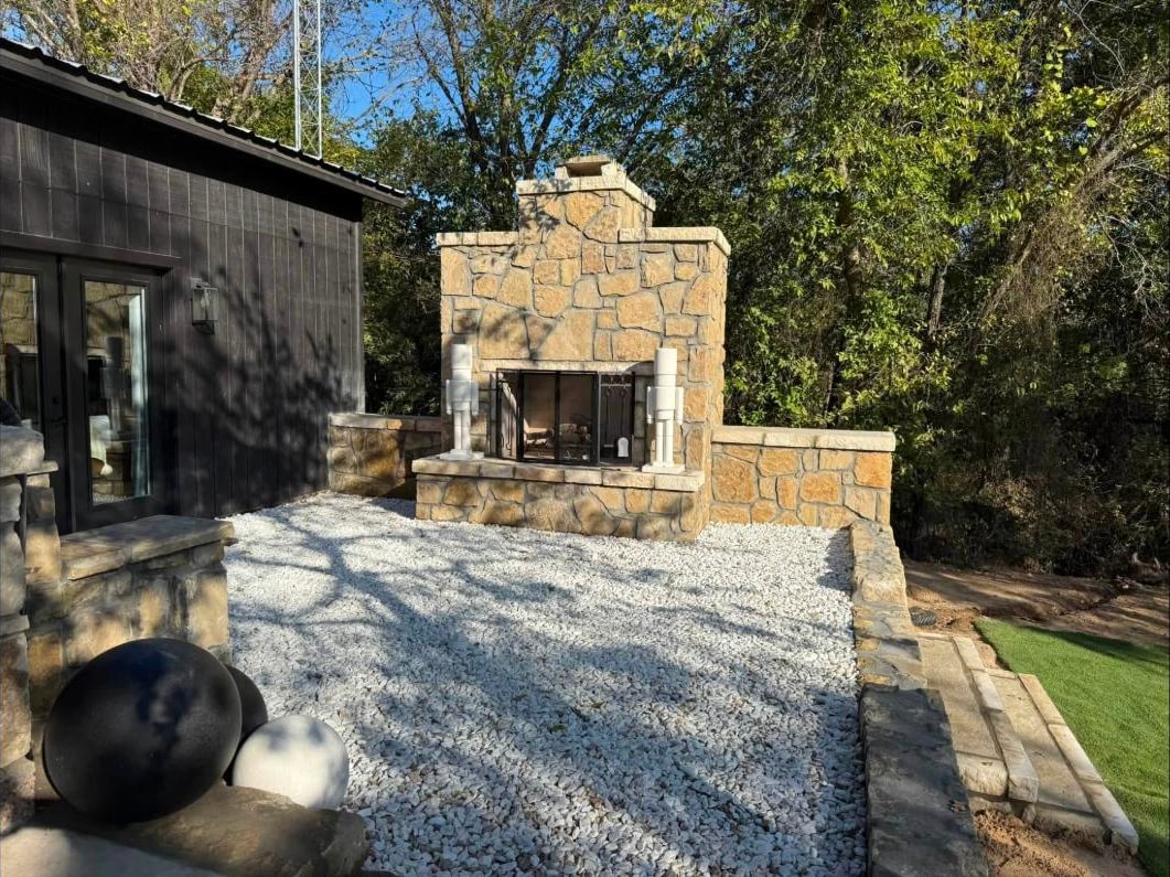 Outdoor stone fireplace anchoring a white gravel courtyard