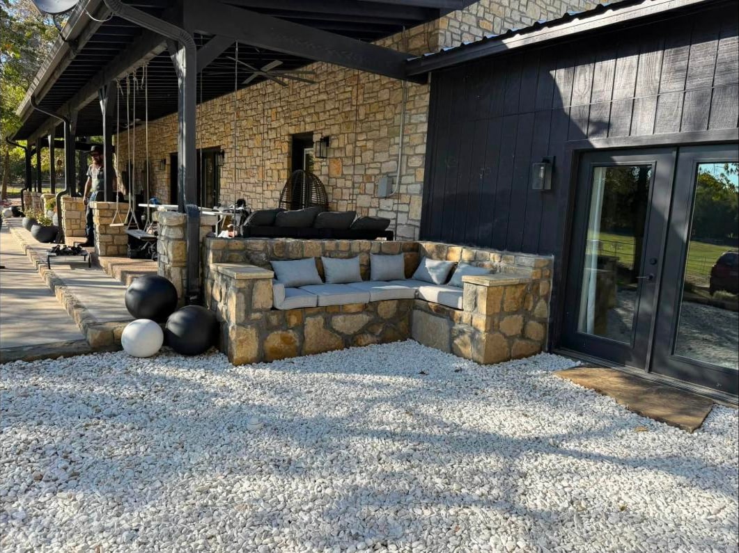 Built in stone banquette seating along a stone veneer wall on white gravel